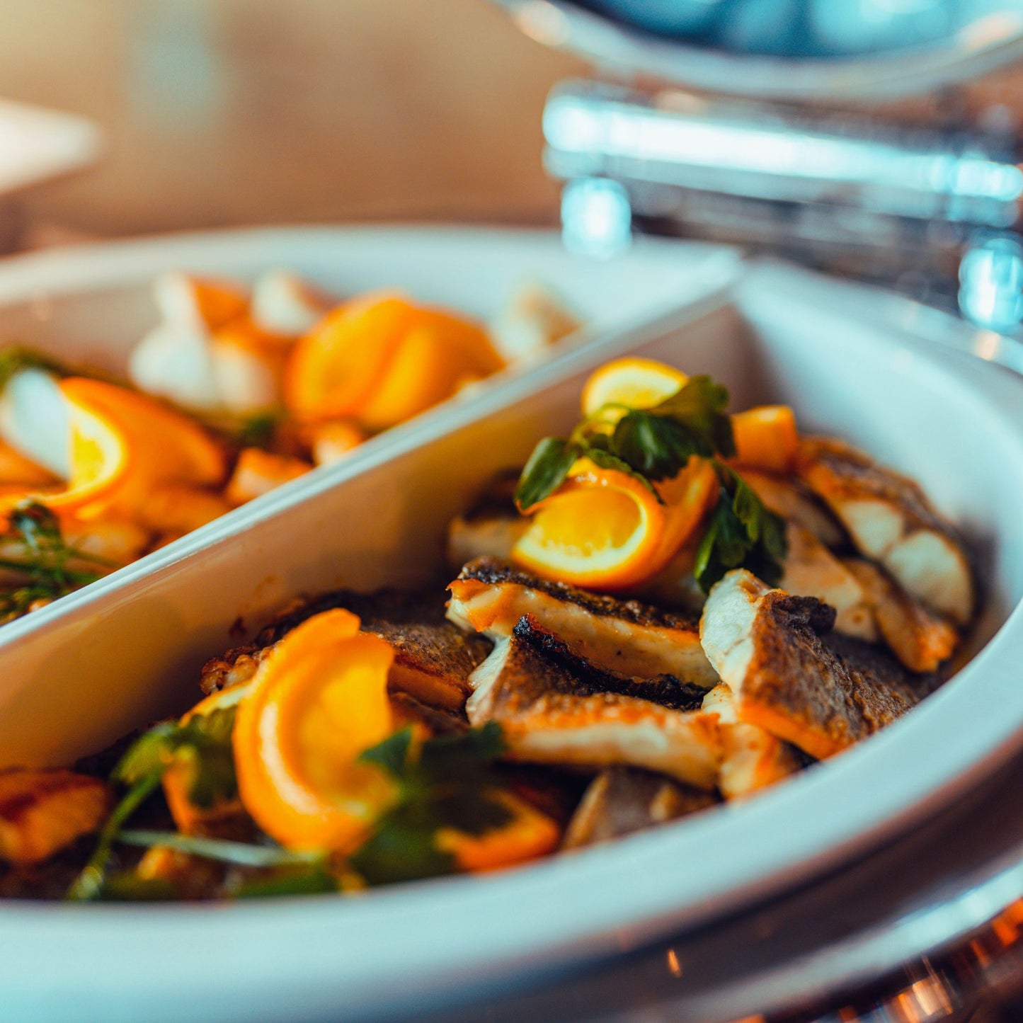 Warmes Fischgericht mit Kräutern und Orangenscheiben garniert.