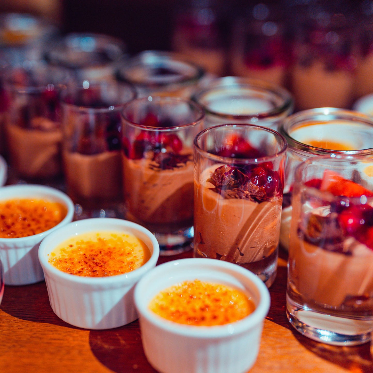 Dessertauswahl mit Crème brûlée in Förmchen und Schokoladenmousse im Glas mit Beeren.