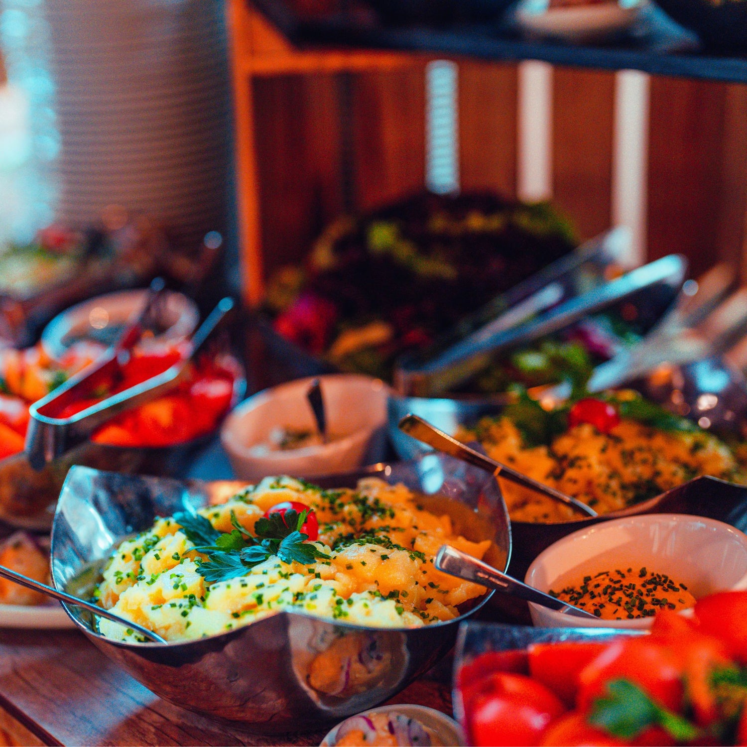 Buffet mit Kartoffelsalat, frischen Kräutern und weiteren Beilagen in Schüsseln.
