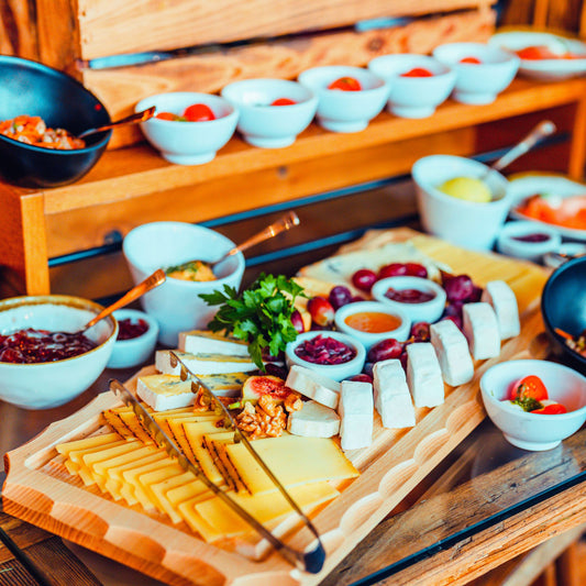 Käseplatte mit verschiedenen Käsesorten, Nüssen, Trauben und kleinen Schälchen mit Chutneys.