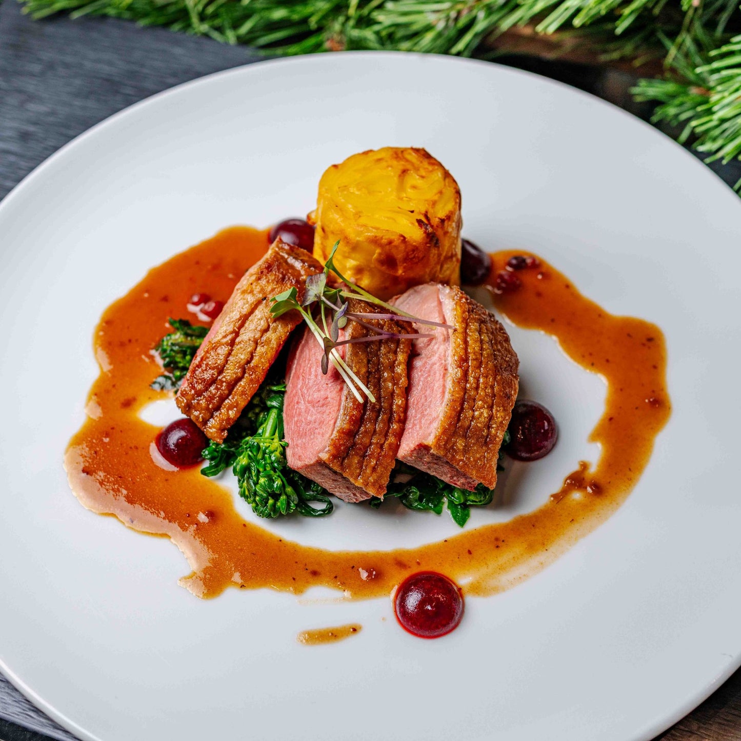 Zart rosa gebratene Entenbrust mit Preiselbeerjus, Brokkoli, Kartoffelgratin und winterlicher Sauce, serviert auf weißem Teller – festliches Gericht aus dem Frozen Wonders Dinner im Airbräu München.