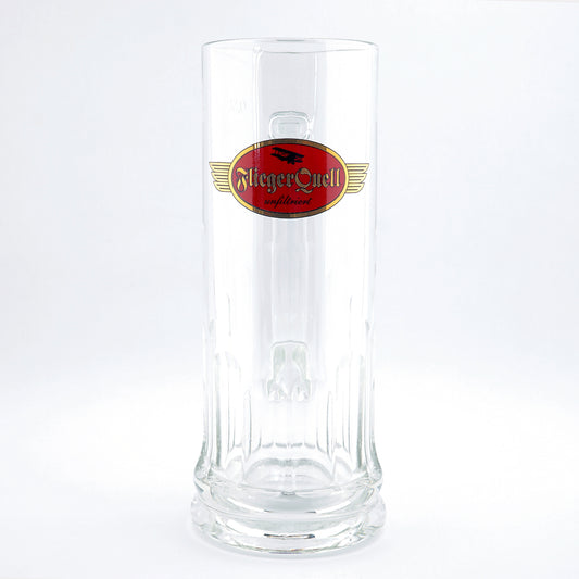 Klares 0,5-Liter-Bierglas mit rotem und goldenen FliegerQuell-Logo sowie Schriftzug „unfiltriert“, auf weißem Hintergrund.